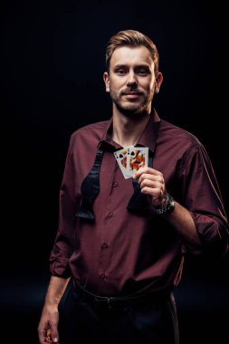 KYIV, UKRAINE - AUGUST 20, 2019: smiling bearded man holding playing cards isolated on black  clipart