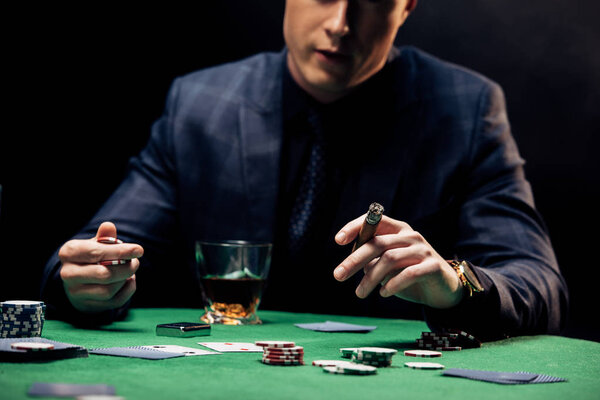 КИЕВ, УКРАИНА - 20 августа 2019 года: обрезанный вид человека, держащего сигару изолированно на черном
 