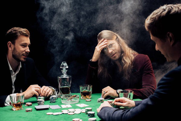 КИЕВ, УКРАИНА - 20 августа 2019 года: избирательное внимание друзей, играющих в покер на черном с дымом
 