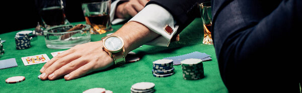 КИЕВ, УКРАИНА - 20 августа 2019 года: панорамный снимок человека, трогающего фишки для покера на покерном столе
 