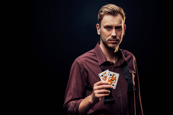 KYIV, UKRAINE - AUGUST 20, 2019: handsome bearded man holding playing cards isolated on black 
