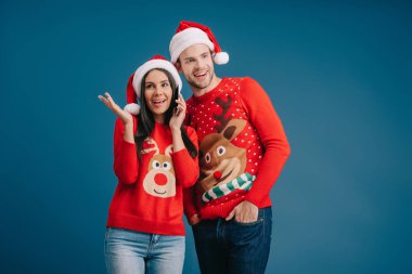 erkek dinlerken santa şapkalı mutlu kadın akıllı telefon konuşuyor, mavi izole