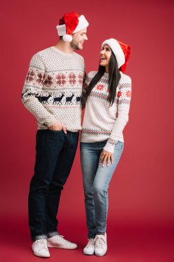 mutlu çift santa şapka ve kazak kırmızı izole sarılma