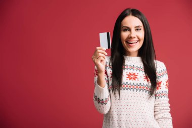 kırmızı izole kredi kartı tutan kış kazak mutlu genç kadın 