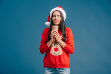 santa şapka kapalı gözleri ve noel kazak gitmek için kahve tutan mutlu kız, mavi izole