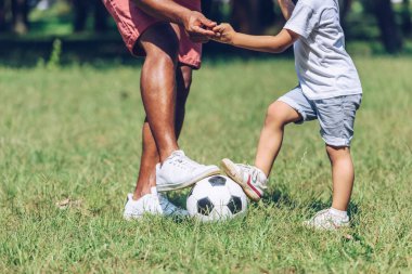 Afrika kökenli Amerikalı baba ve oğlunun parkta futbol oynamaları.