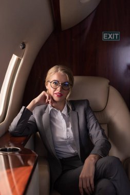 beautiful businesswoman sitting in plane during business trip clipart