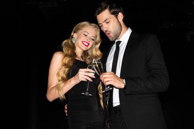 Şampanyayla kadeh tokuşturan güzel bir çift. 