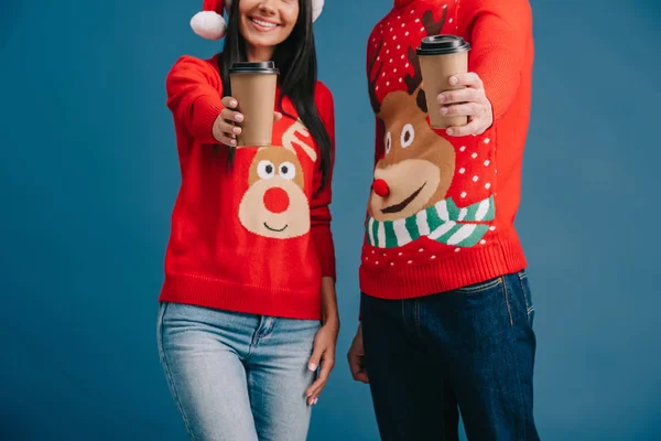 青で孤立して行くためにコーヒーを保持しているクリスマスセーターのカップルのトリミングビュー — ストック写真