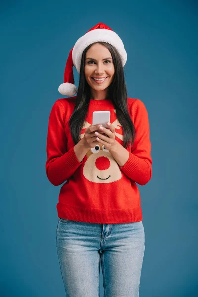 Smiling Woman Santa Hat Christmas Sweater Using Smartphone Isolated Blue — Stock Photo, Image