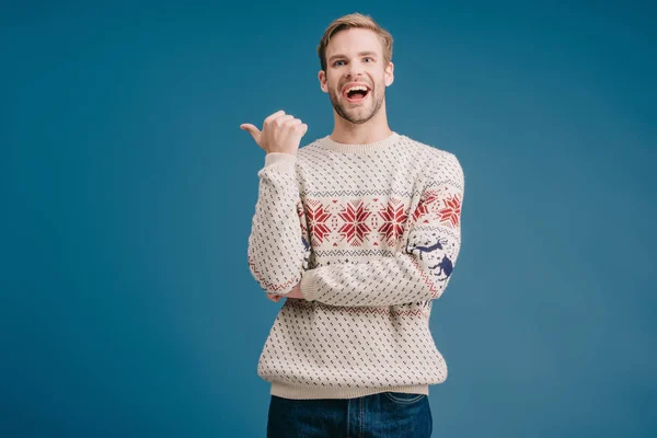 Lachender Mann Winterpullover Zeigt Auf Etwas Vereinzeltes Auf Blauem Grund — Stockfoto