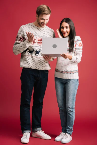 Pareja Sorprendida Suéteres Invierno Utilizando Portátil Aislado Rojo — Foto de Stock