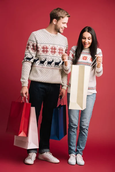 Happy Couple Winter Sweaters Holding Shopping Bags Isolated Red — Stock Photo, Image