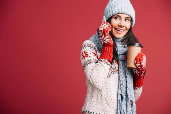 冬服を着た笑顔の女性がスマートフォンで話し コーヒーを持って赤で孤立 — ストック写真