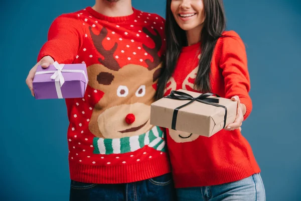 青で隔離されたクリスマスギフトボックスを保持するセーターのカップルのトリミングビュー — ストック写真