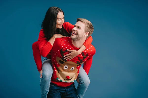 Cheerful Couple Christmas Sweaters Piggybacking Isolated Blue — Stock Photo, Image