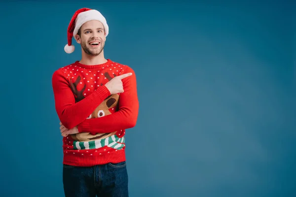 Cheerful Man Santa Hat Christmas Sweater Pointing Isolated Blue — Stock Photo, Image
