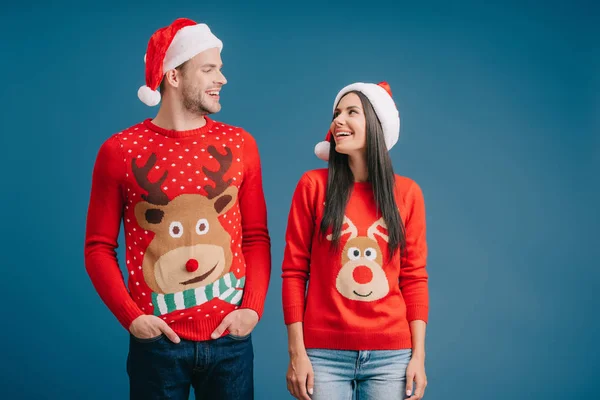 Lachen Paar Poseren Santa Hoeden Truien Geïsoleerd Blauw — Stockfoto