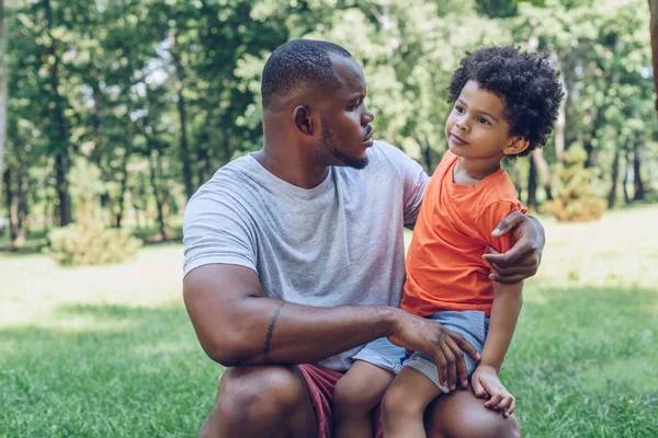 Cute African American Boy Sitting Fathers Knee Park — Stock Photo, Image