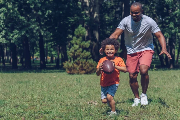 Şirin Afrikalı Amerikalı Çocuk Babamla Parkta Eğlenirken Rugby Topuyla Koşuyor — Stok fotoğraf