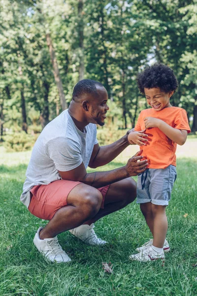 明るいアフリカ系アメリカ人の父親と息子は公園で楽しみながら笑っています — ストック写真