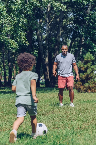 公園で可愛い息子とサッカーをしている若いアフリカ系アメリカ人の父親 — ストック写真