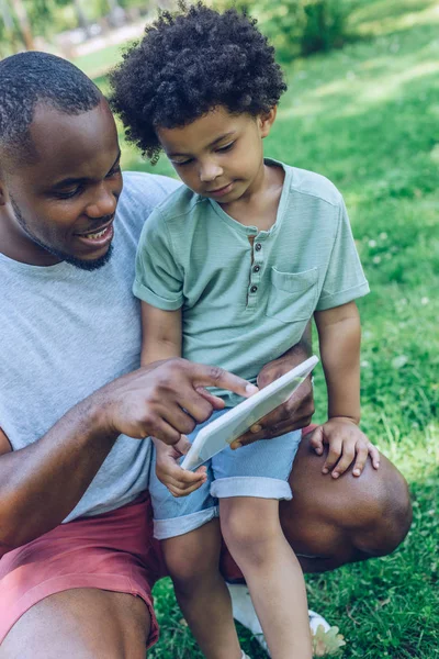 Sorridente Afro Americano Homem Mostrando Digital Tablet Para Adorável Filho — Fotografia de Stock