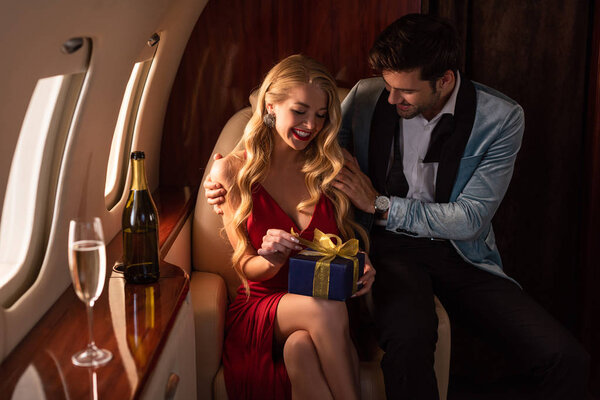 handsome man presenting gift to attractive sexy woman in plane