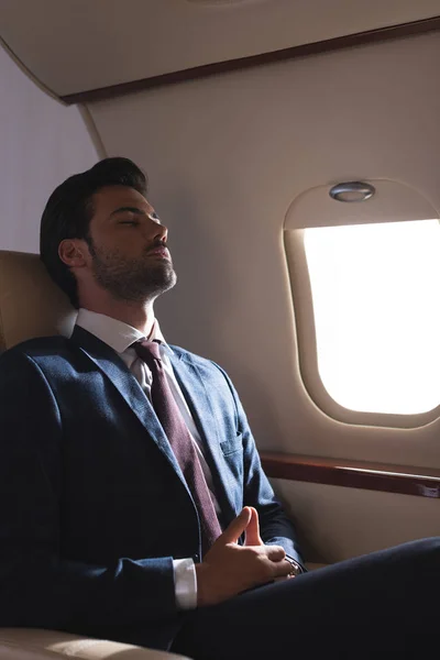 商务旅行时穿着西装睡在飞机上的商人 — 图库照片
