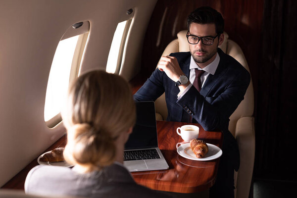 корпоративные предприниматели, работающие с ноутбуками в самолете
 