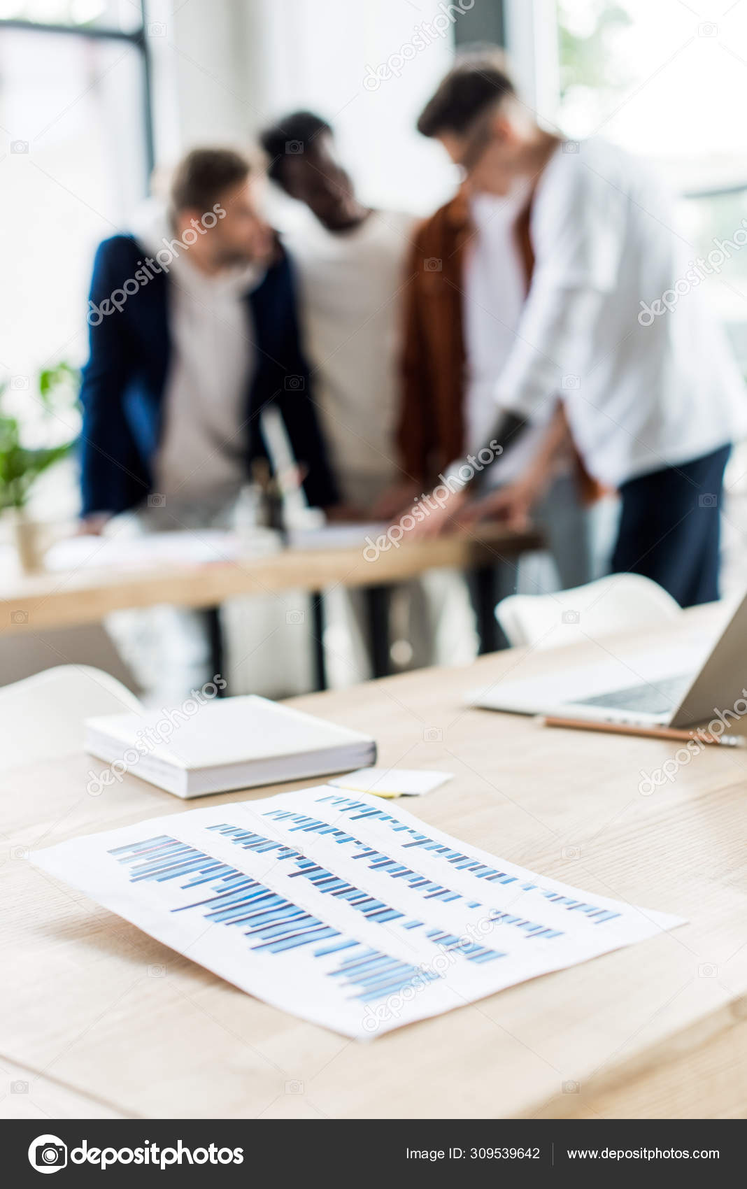 Selective focus paper graphs charts desk businesspeople standing 
