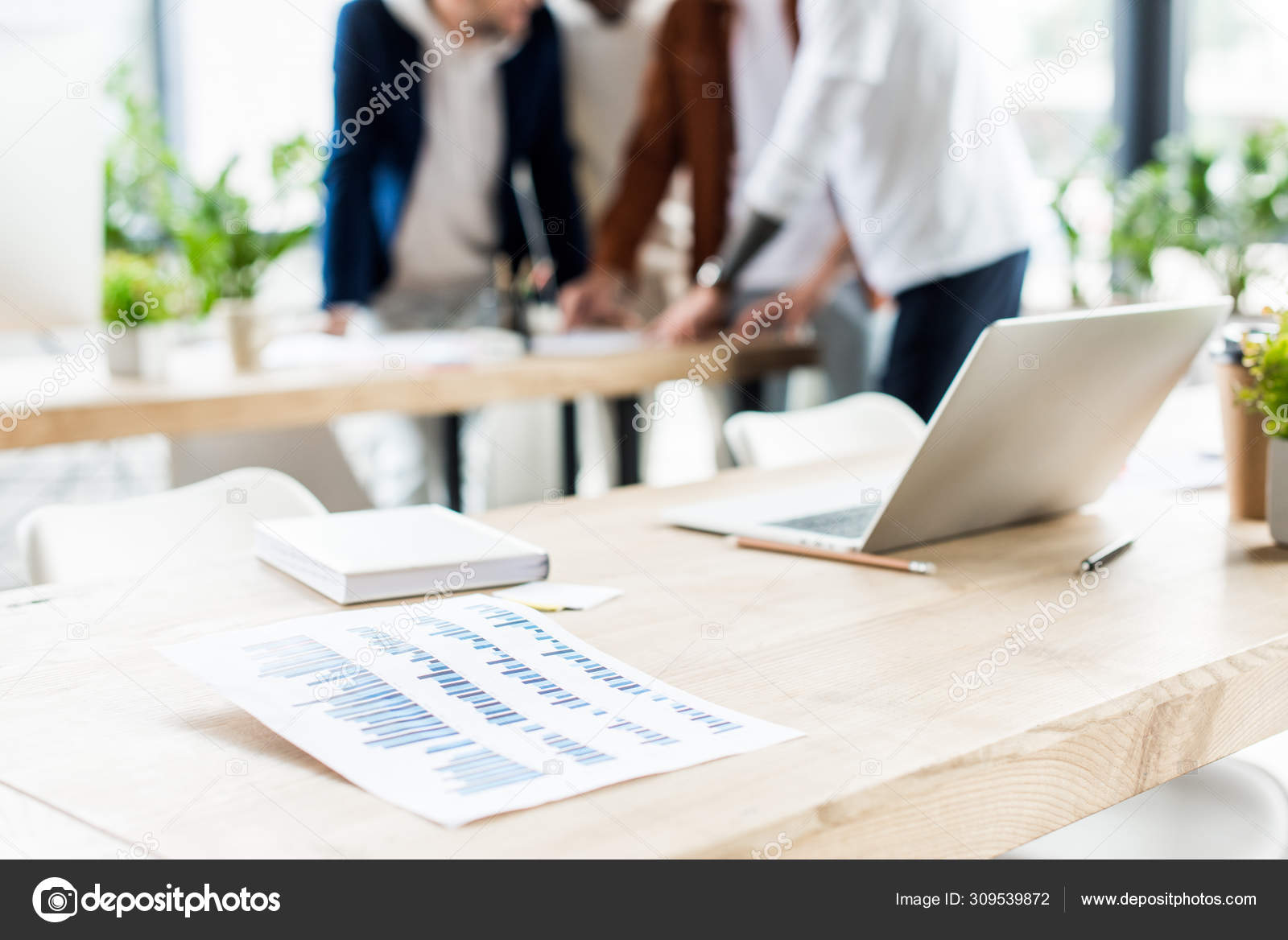 Selective focus desk laptop notebook paper graphs charts businesspeople 