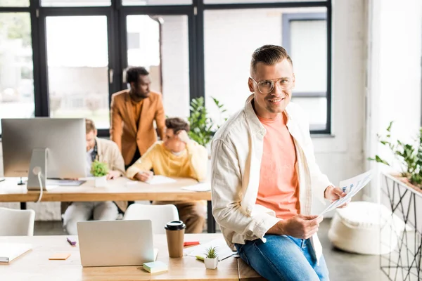 Bonito Jovem Empresário Olhando Para Câmera Enquanto Sentado Mesa Perto — Fotografia de Stock