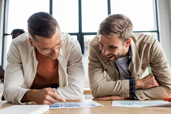 Dos Jóvenes Hombres Negocios Sonrientes Analizando Documentos Con Gráficos Gráficos —  Fotos de Stock