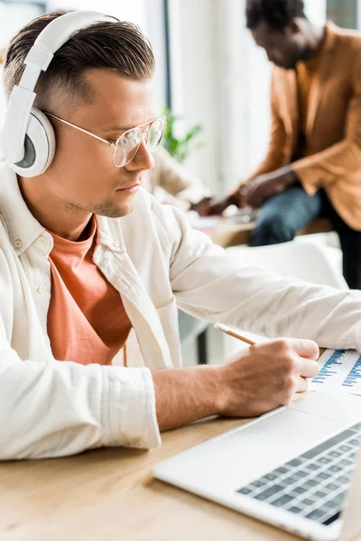 Serious Businessman Headphones Analyzing Graphs Charts Using Laptop Office — Stock Photo, Image