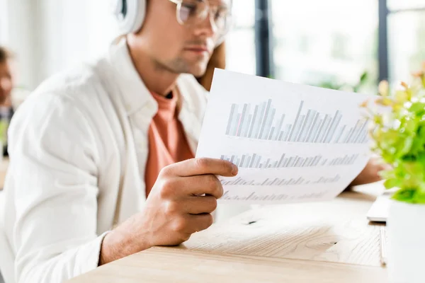Selective Focus Young Businessman Sitting Headphones Analyzing Paper Graphs Charts — ストック写真
