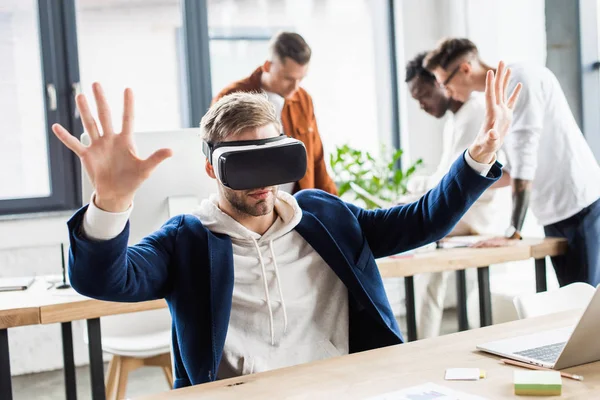 Young Businessman Using Headset Gesturing While Multicultural Colleagues Working Office — Stock Photo, Image