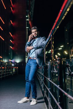 yakışıklı işadamı resmi giyim akıllı telefon üzerinde konuşurken ve gece şehirde kağıt bardak tutarak  