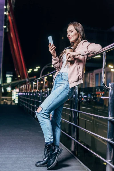 Mujer Sonriente Con Chaqueta Rosa Usando Smartphone Sosteniendo Taza Papel — Foto de Stock