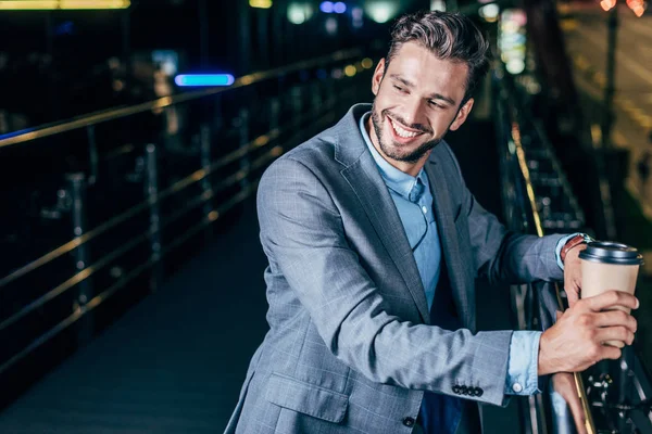 Красивий Бізнесмен Офіційному Одязі Посміхається Тримає Паперовий Стаканчик Нічному Місті — стокове фото