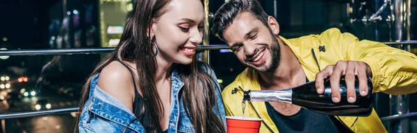 Panoramic Shot Handsome Smiling Boyfriend Pouring Champagne Plastic Cup Night — Stock Photo, Image
