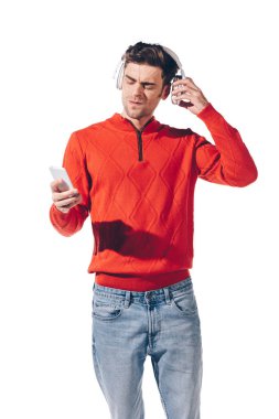 Kafası karışmış, kulaklıkla müzik dinleyen ve akıllı telefon kullanan beyaz tenli bir adam.