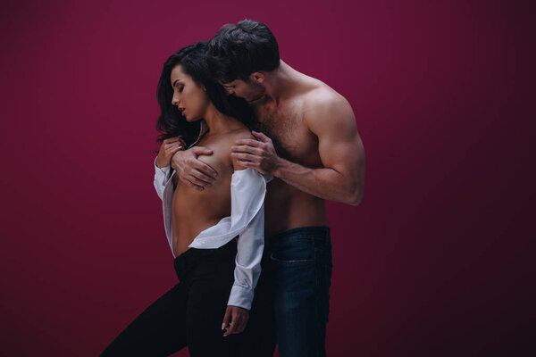 shirtless man embracing sexy girl in unbuttoned white shirt on dark background