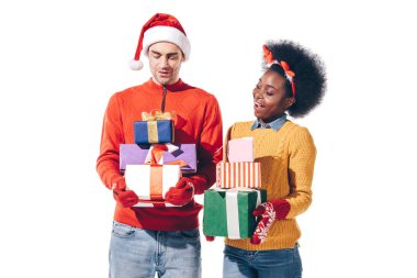 Noel Baba şapkalı ve geyik boynuzlu mutlu bir çift Noel hediyeleri taşıyor.