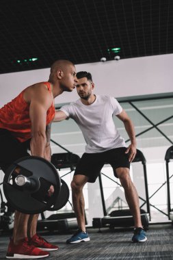 Afrika kökenli Amerikalı sporcuyu destekleyen özenli antrenör halter kaldırıyor.