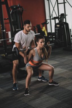 Genç sporcuyu destekleyen dikkatli antrenör halter kaldırıyor.