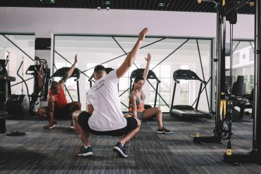 Eğitmenlerin çok kültürlü sporcularla el kaldırarak çömelmelerinin arka planı