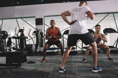 Spor salonunda antrenörlerin çok kültürlü sporcularla birlikte ısınması.