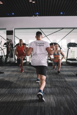 Kişisel antrenörlerin çok kültürlü sporcularla birlikte hamleler yaptığı arka plan görüntüsü