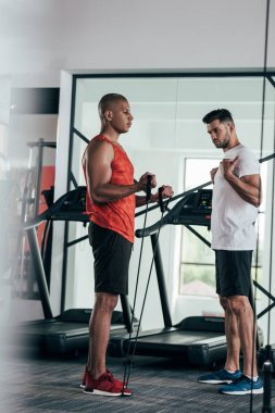 Afrika kökenli Amerikan sporcusuna direniş bandıyla egzersiz yaptıran özenli antrenör.